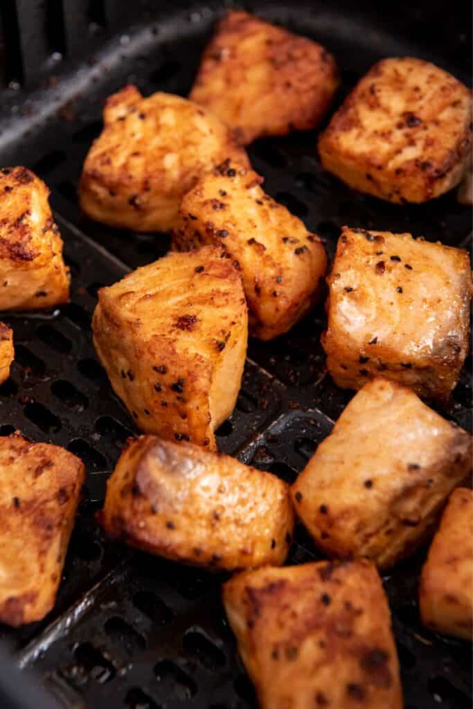 Close up of air fryer salmon bites in an air fryer basket.
