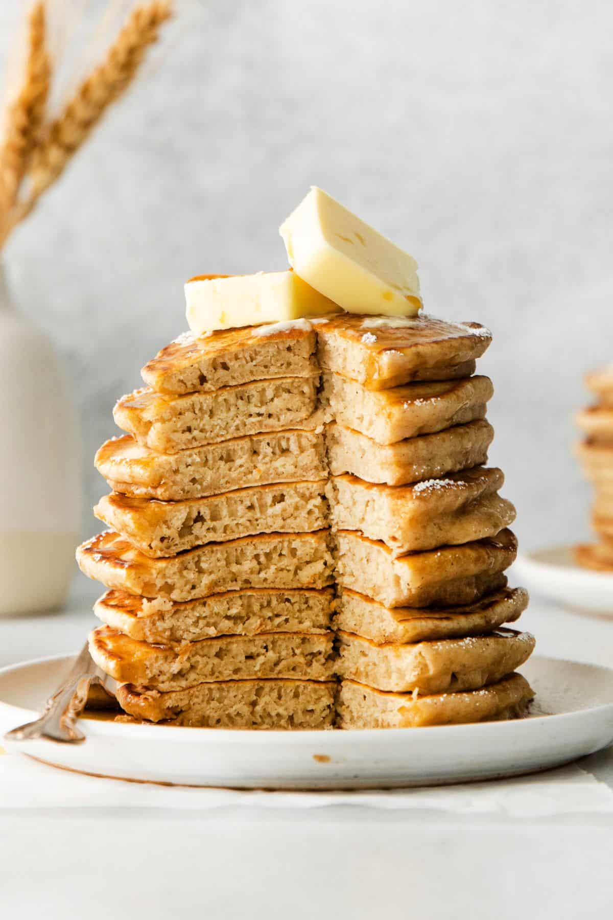 The pancakes stacked on a plate with a chunk of them out so you can see the fluffy inside.