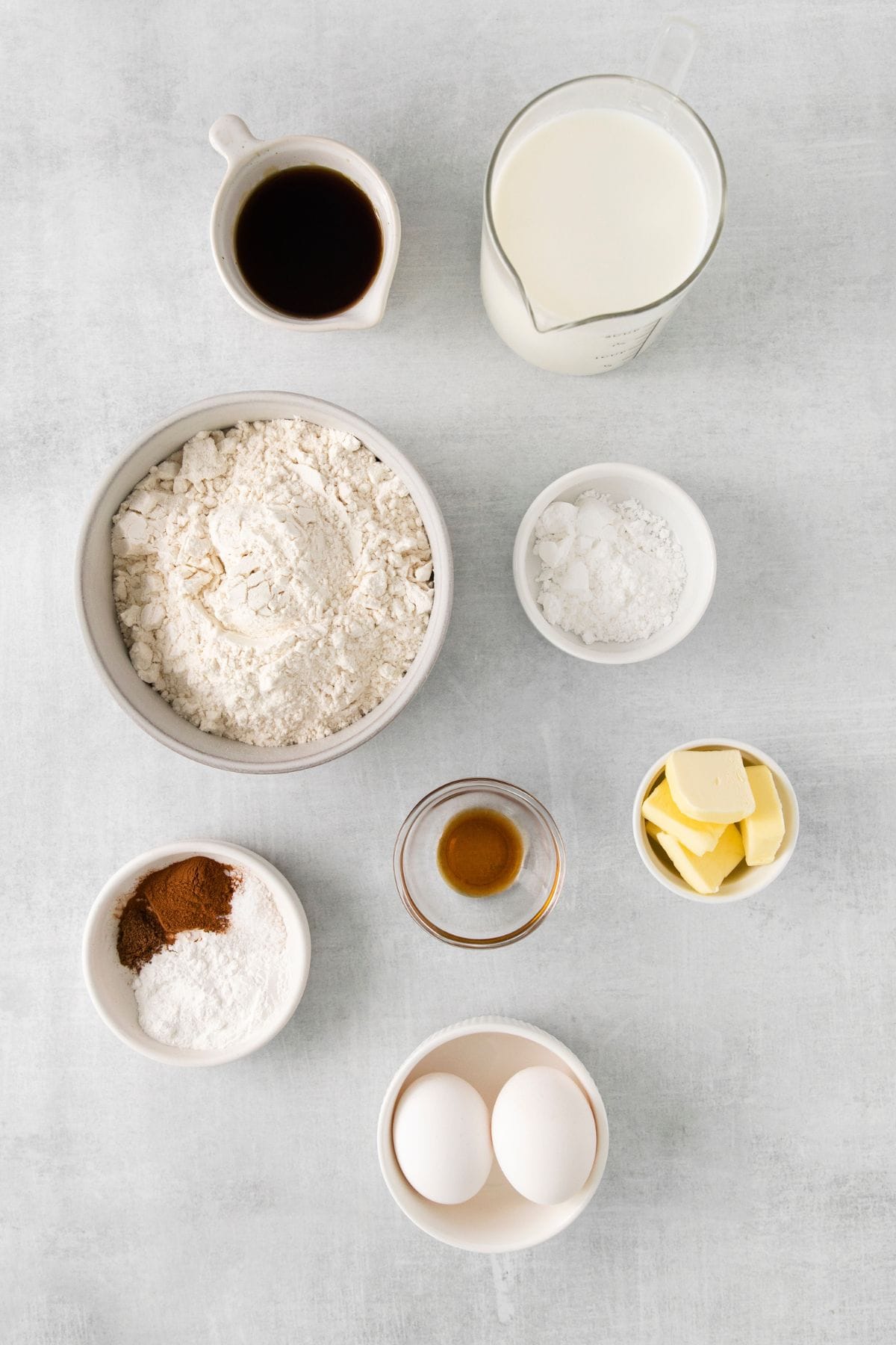 Ingredients needed to make french toast with pancake batter: milk, butter, maple syrup, eggs, vanilla, flour, baking powder, cinnamon, nutmeg, salt, and powdered sugar.
