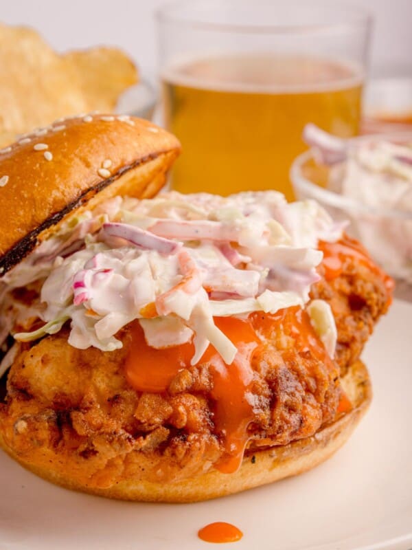 Buffalo chicken sandwich with coleslaw on top with the bun half on.