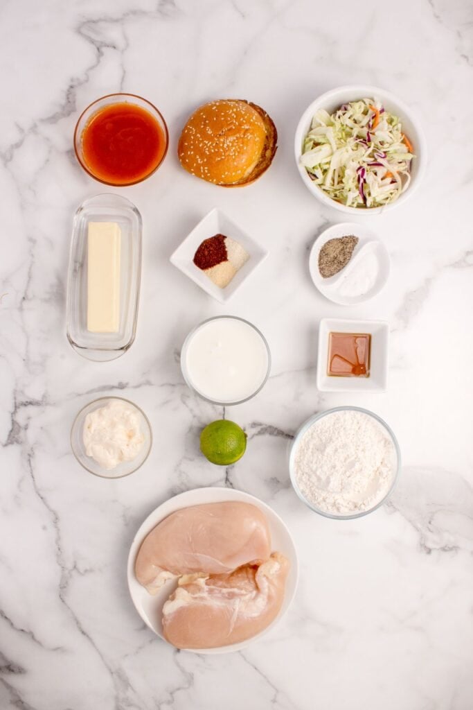 Ingredients needed to make a buffalo chicken sandwich: chicken breasts, buttermilk, seasonings, flour, buffalo sauce, butter, honey, coleslaw mix, ranch, lime juice, sandwich buns, and oil.