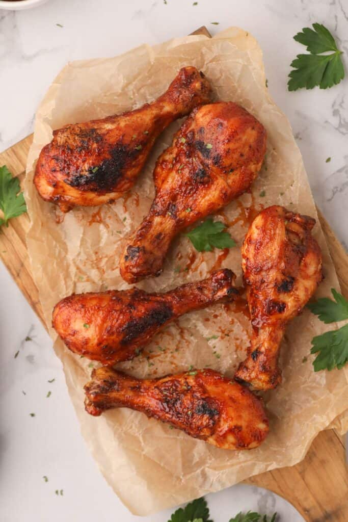 Air fryer chicken drumsticks on a a cutting board with brown parchment paper underneath.