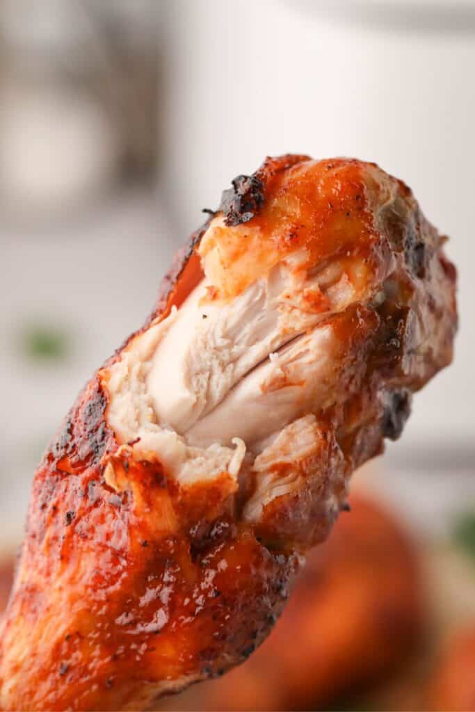 Close up of an air fryer chicken drumstick with a bite taken out of it.