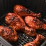 Close up of cooked air fryer chicken drumsticks in the air fryer basket.
