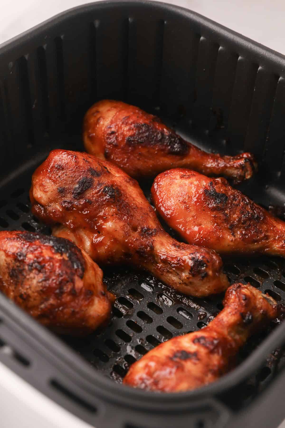 Close up of cooked air fryer chicken drumsticks in the air fryer basket.