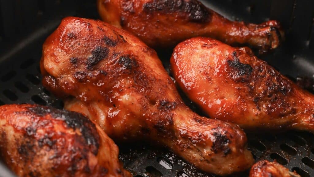 Close up of cooked air fryer chicken drumsticks in the air fryer basket.