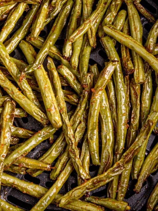 Close up of cooked air fryer green beans in the air fryer basket.