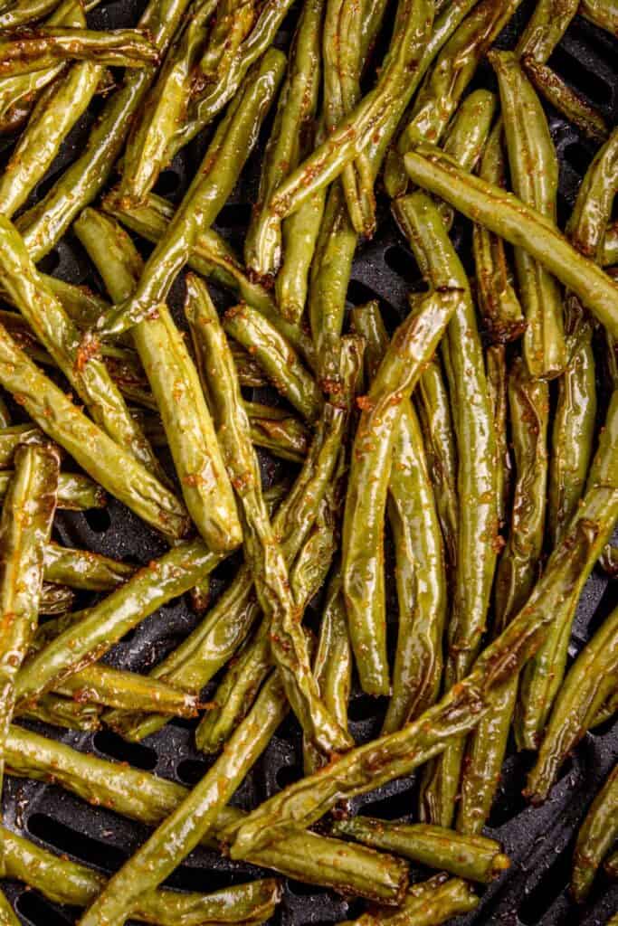 Close up of cooked air fryer green beans in the air fryer basket.