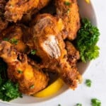 air fried chicken on plate with a bite taken out of a drumstick