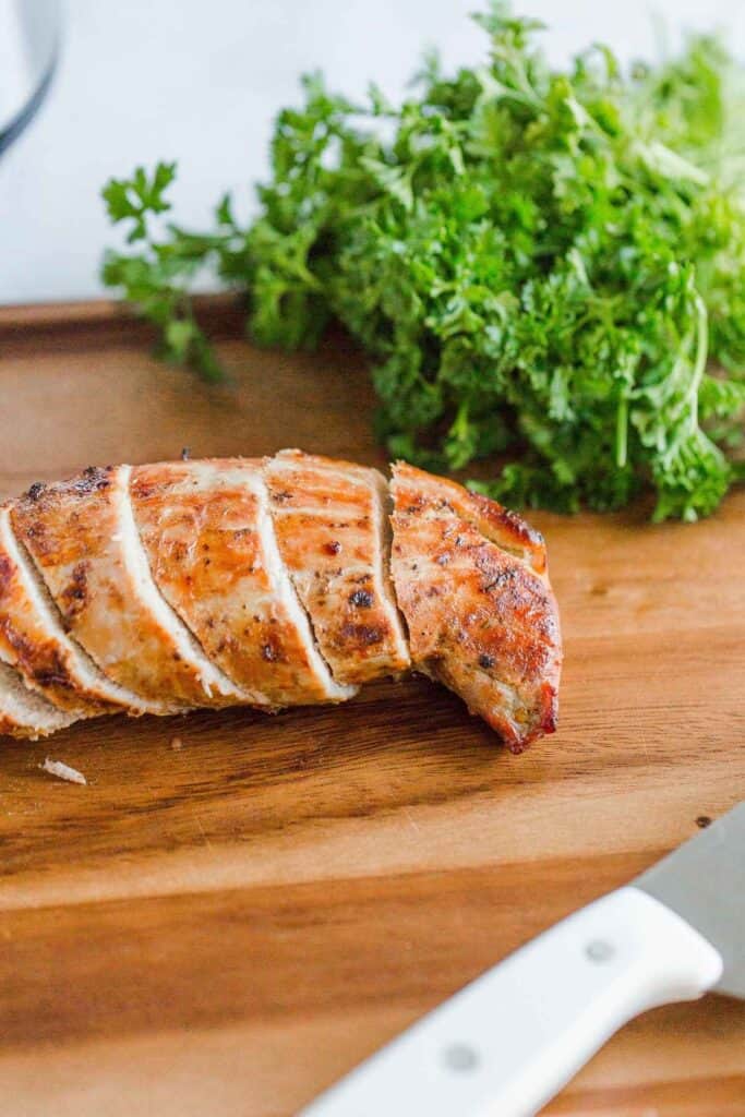 Air fryer pork tenderloin cut on a cutting board.