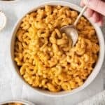 Person taking a spoonful of macaroni and cheese without milk from a bowl of mac and cheese.