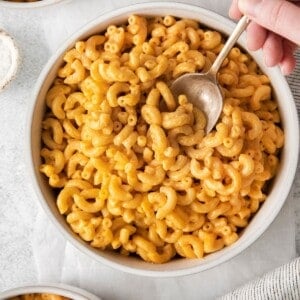 Person taking a spoonful of macaroni and cheese without milk from a bowl of mac and cheese.
