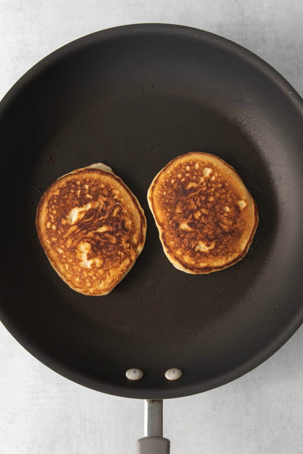 Sweet cream pancakes cooking on a griddle pan.