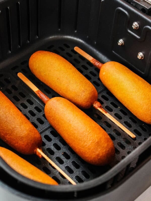 Cooked corn dogs in the air fryer basket.