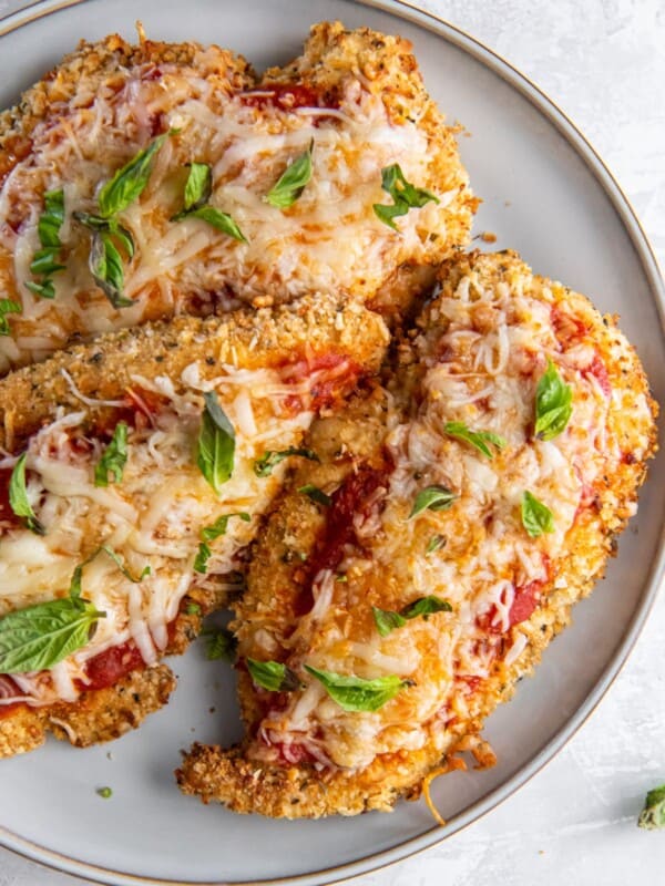 Close-up of air fryer chicken Parmesan on a white plate.