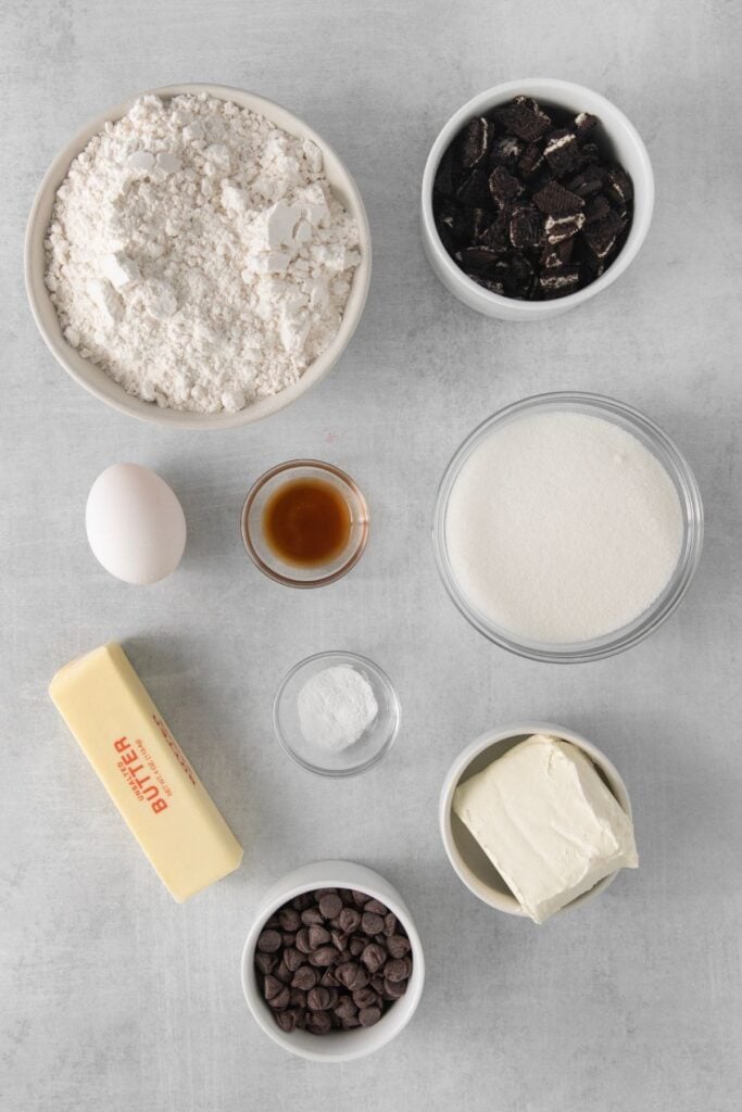 Ingredients needed to make Oreo cheesecake cookies: butter, cream cheese, sugar, egg, vanilla, flour, baking soda, Oreos, and chocolate chips.