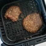 Overhead view of two cube steaks in an air fryer basket.
