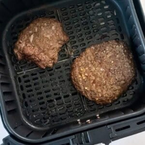 Overhead view of two cube steaks in an air fryer basket.