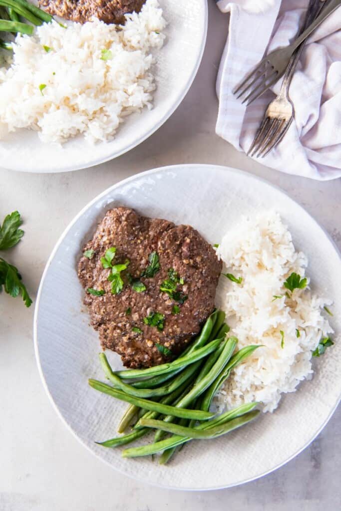 Overhead view of cube steak with rice and green beans.
