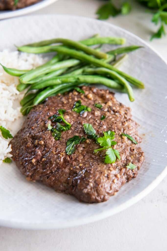 Cube Steak with rice and green beans on a white plate.