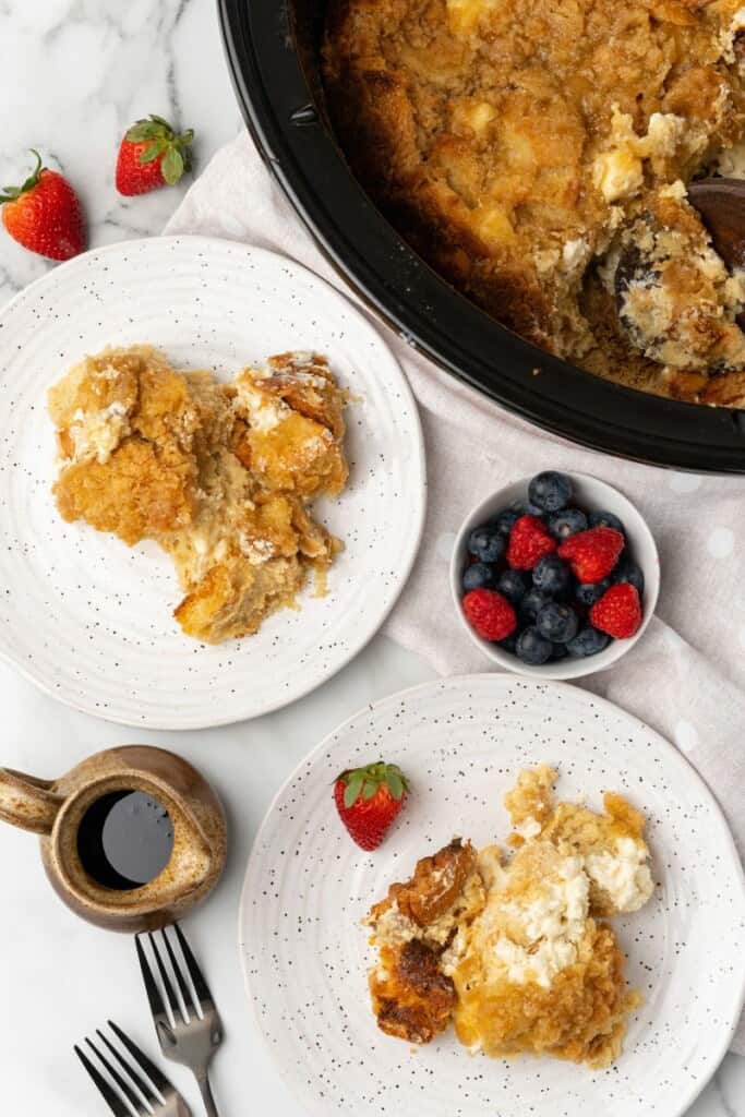 Overhead view of 2 white plates each with a single serving of crockpot french toast casserole on them.