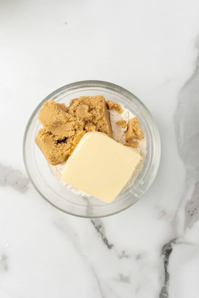 Overhead view of eggs, milk, brown sugar, vanilla, and salt in a clear mixing bowl.