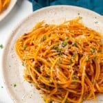 Overhead view of spaghetti on an off white plate.