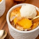 An individual serving of peach cobbler in a small white dessert dish.