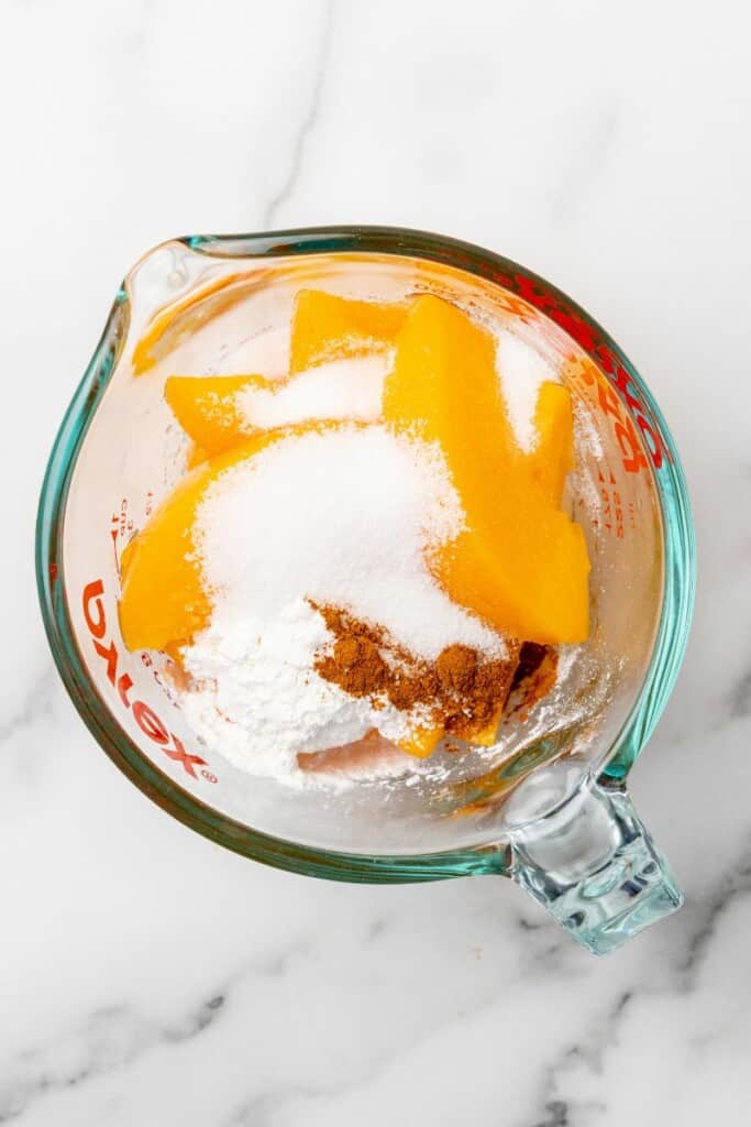 Peaches, sugar, cornstarch, and cinnamon in a small mixing bowl