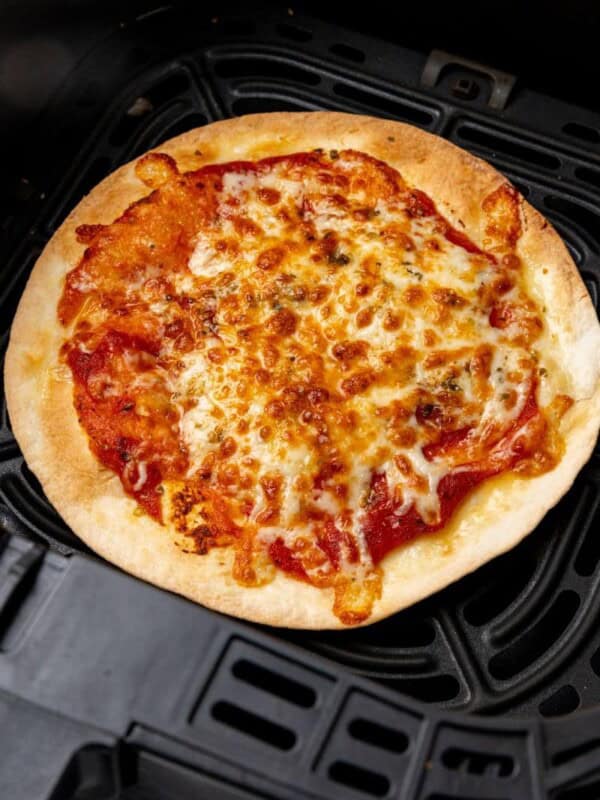 Tortilla pizza prepared in an air fryer resting in a black basket.