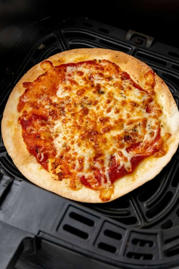 Tortilla pizza prepared in an air fryer resting in a black basket.