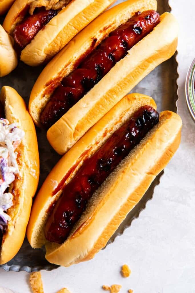Close up view of two grilled bbq hot dogs in buns.