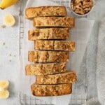 Loaf of banana bread cut into slices on a cooling rack.