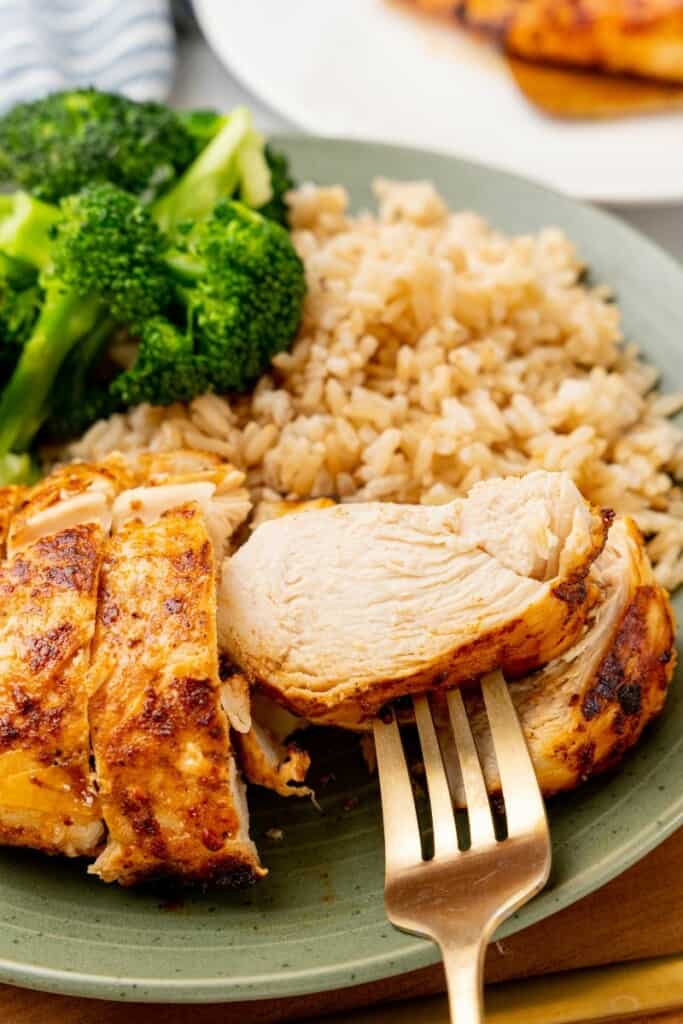 A closeup view of a fork holding a bite of chicken.