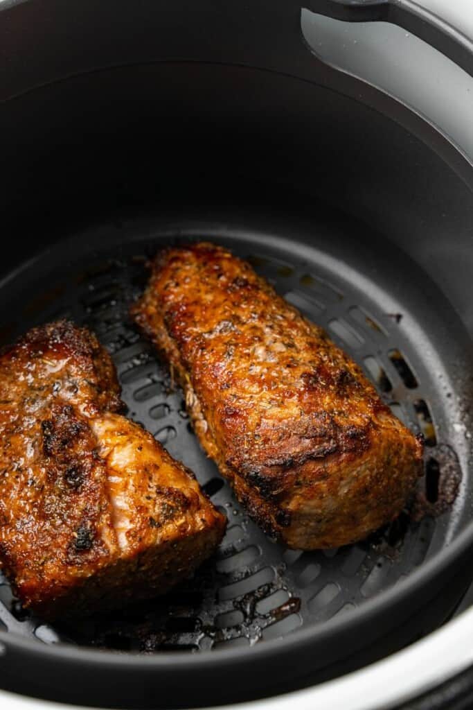 Prepared pork tenderloin resting in a black ninja foodi basket.