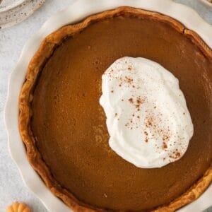 Pumpkin pie without evaporated milk with a big dollop of whipped cream on top.