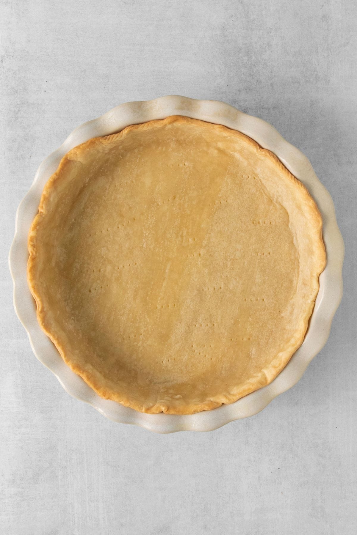 Pie crust in a pie plate after being pre-baked to show how the rice kept it flat.