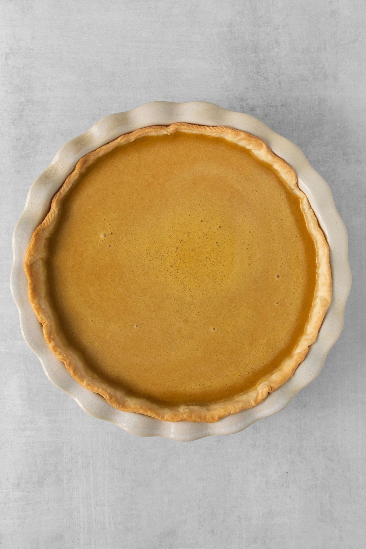 Pumpkin pie batter poured into the pie crust about to be baked.