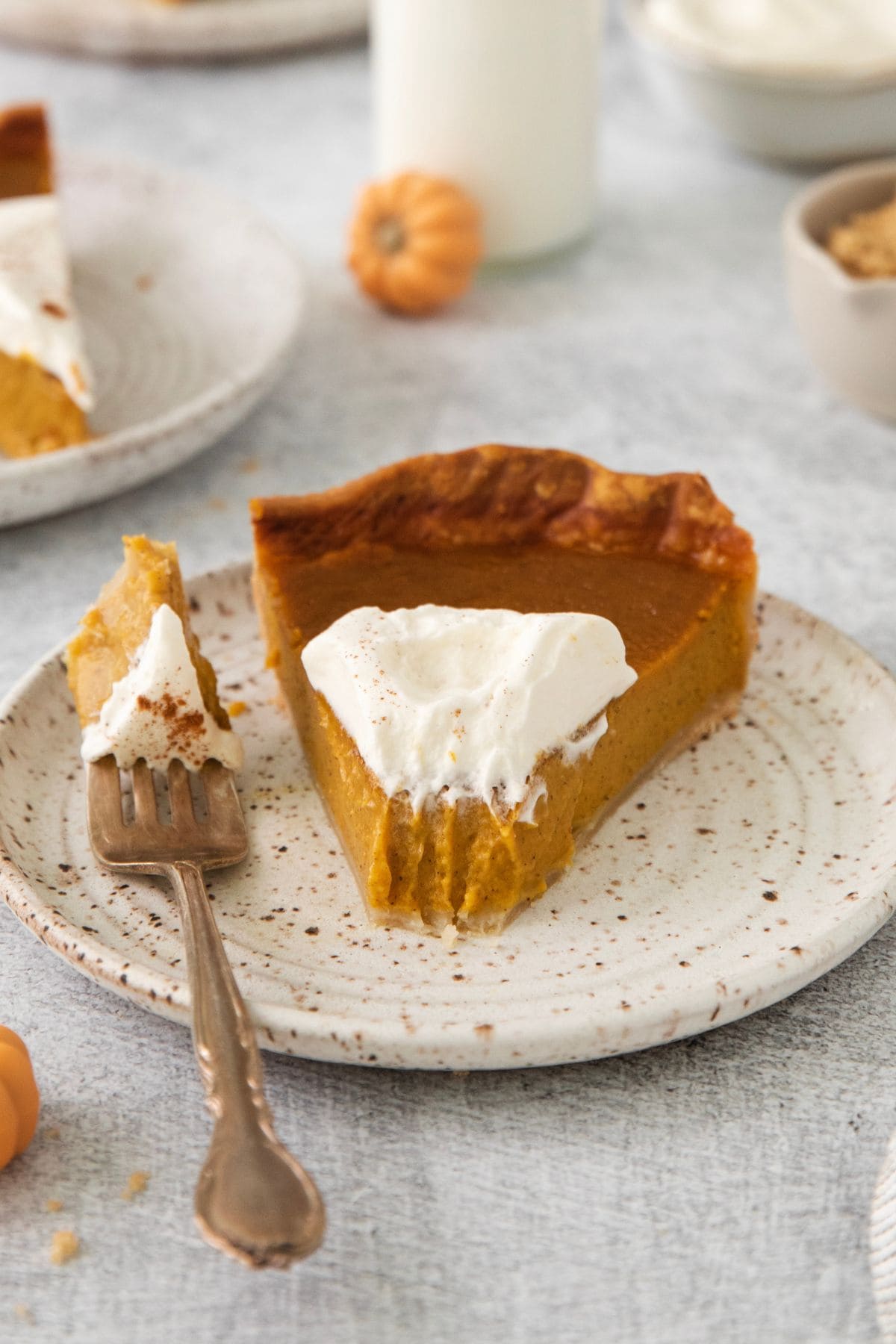 Easy pumpkin pie recipe slice on a plate with a piece taken off with a fork to the side so you can see the texture of the pie.