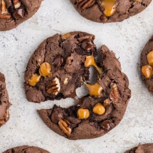 Close up of the turtle cookie recipe with the middle one split in half so you can see the melted chocolate chips and caramel bits stretching.