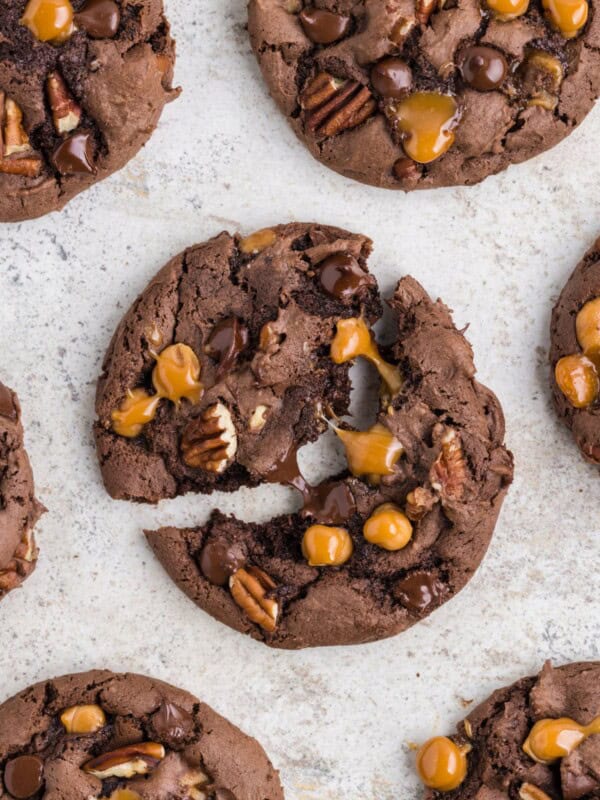 Close up of the turtle cookie recipe with the middle one split in half so you can see the melted chocolate chips and caramel bits stretching.