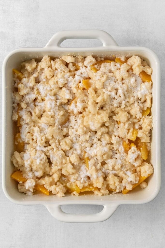 Peach cobbler with canned peaches with crumble topping about to be baked.