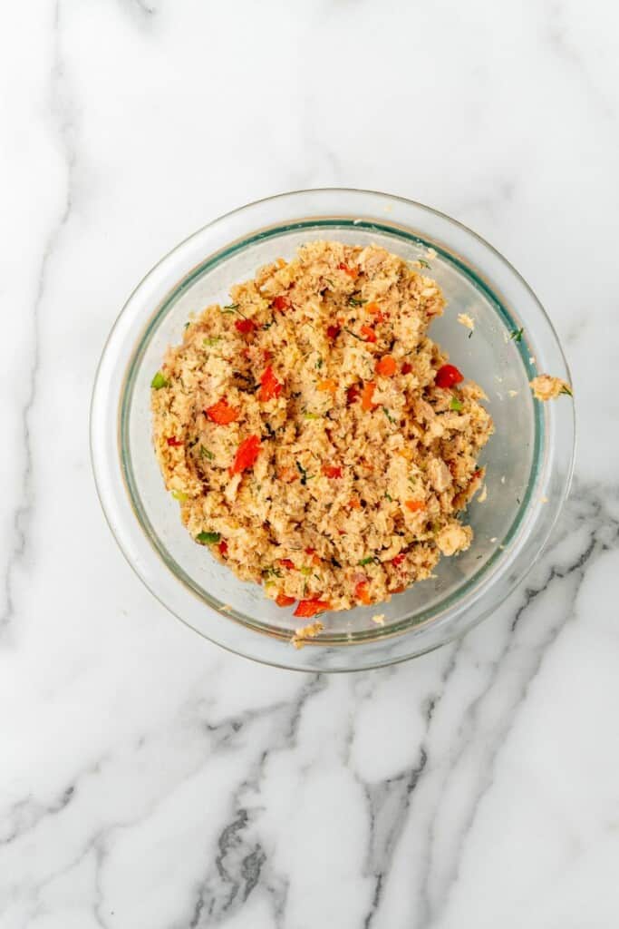 The combined ingredients for salmon patties in a clear mixing bowl.