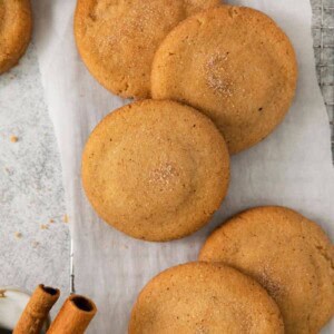 Snickerdoodles with Brown Butter on parchment paper with cinnamon sticks