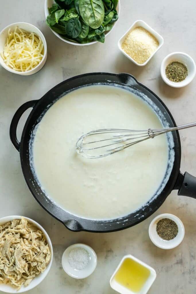 Alfredo sauce being prepared in a saucepan.