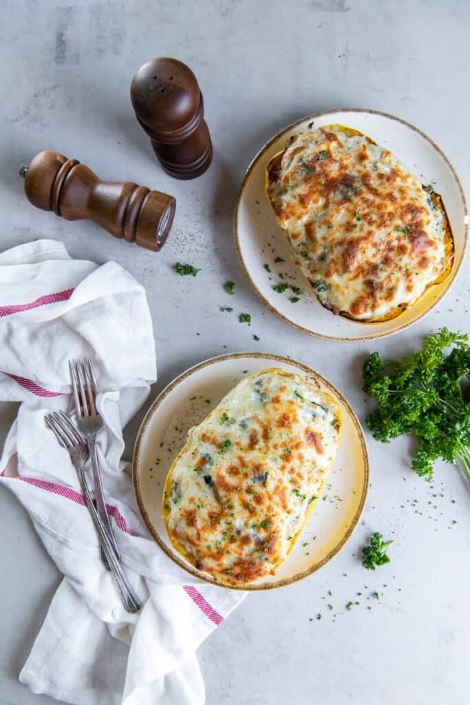 Overhead view of two plates each holding a spaghetti squash stuffed with chicken alfredo.