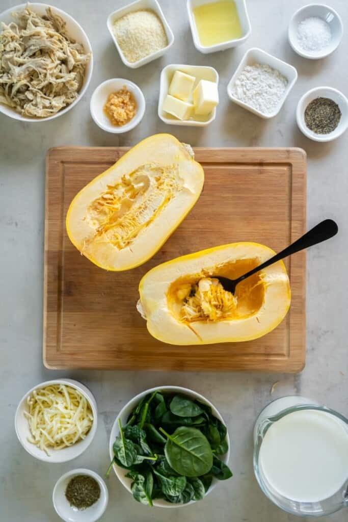 A spaghetti squash sliced in half with a spoon to scoop out the inside.
