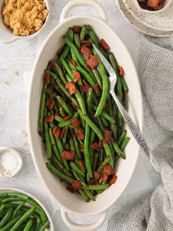 Green beans with bacon in an oblong serving dish with a fork.