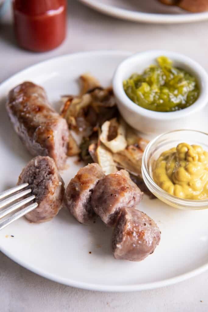 Closeup view of a brat cut into slices with a fork holding on piece.