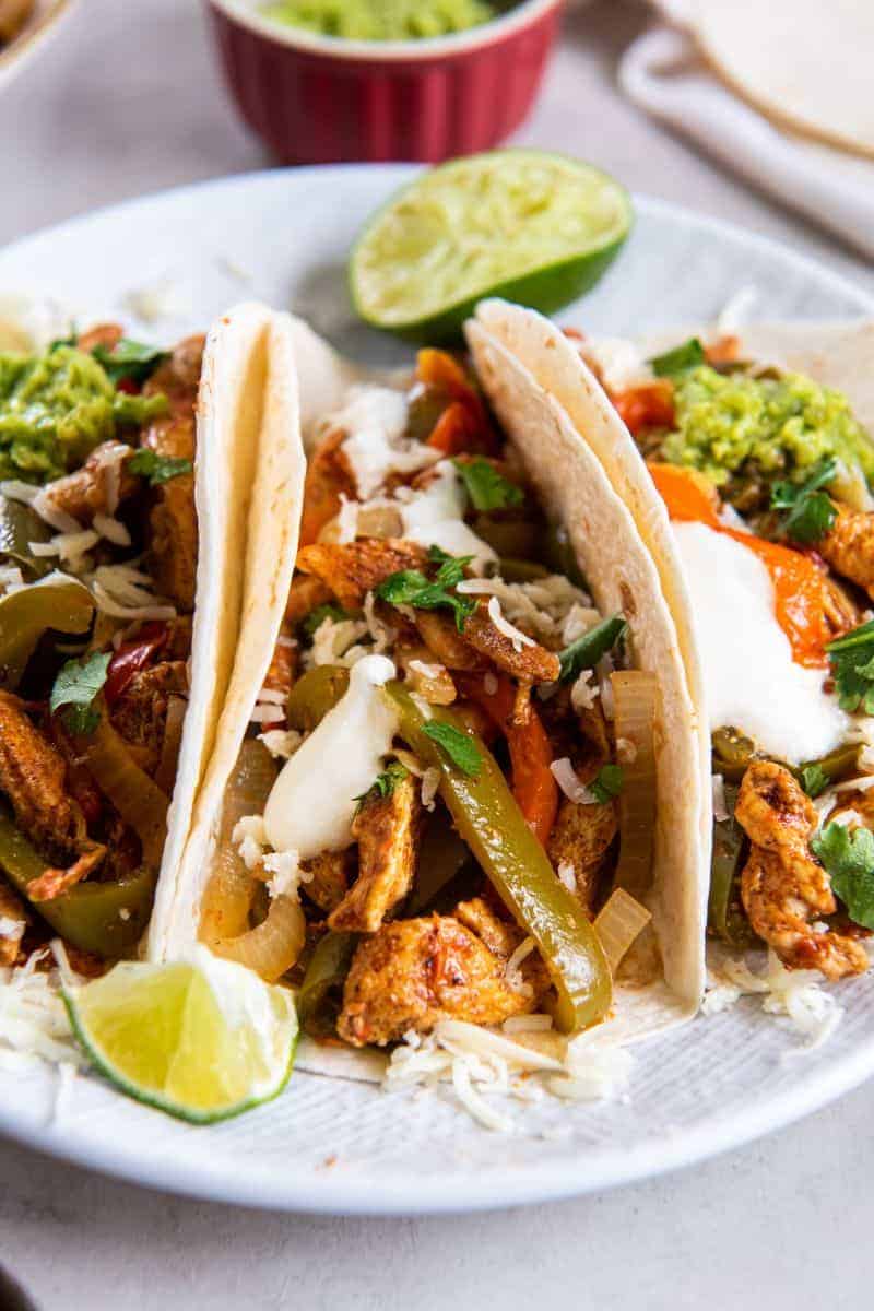 Closeup view of chicken fajitas on a white plate ready to be enjoyed.